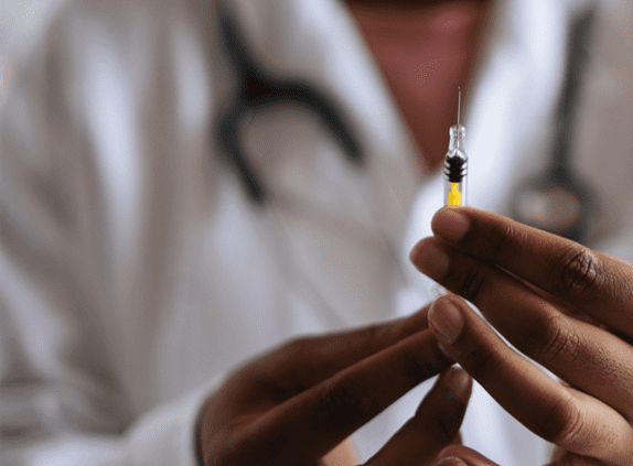 Woman in lab coat holding syringe