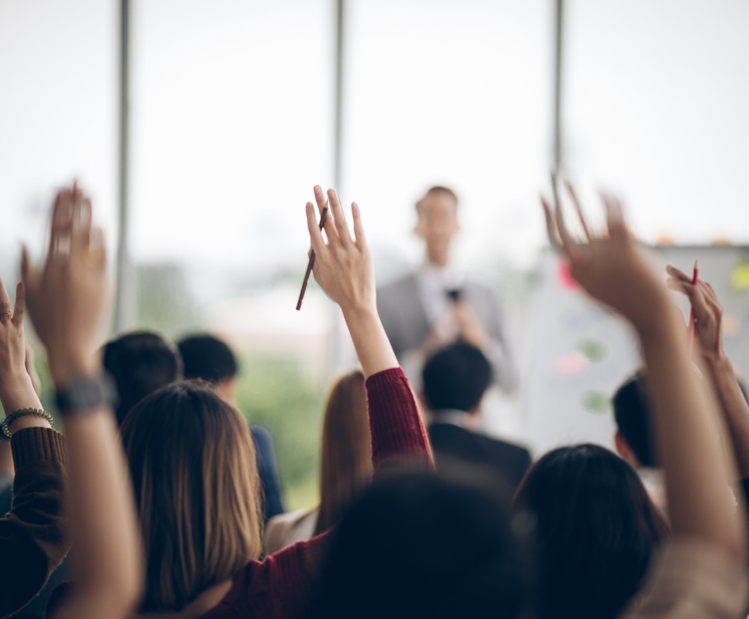 People in a seminar with their hands up